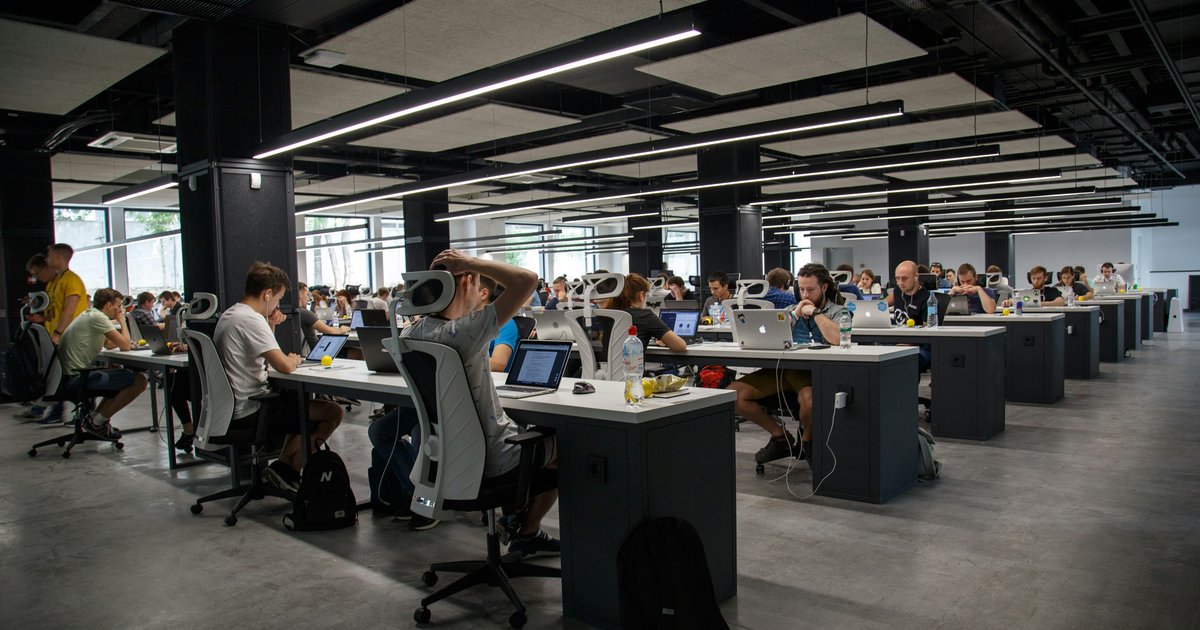 A busy tech company open-plan office with people working at their desks